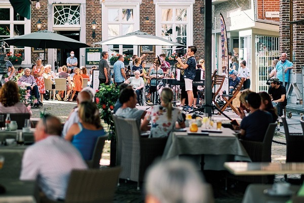 Bandjes spelen muziek voor een vol terras op de Markt in Maaseik