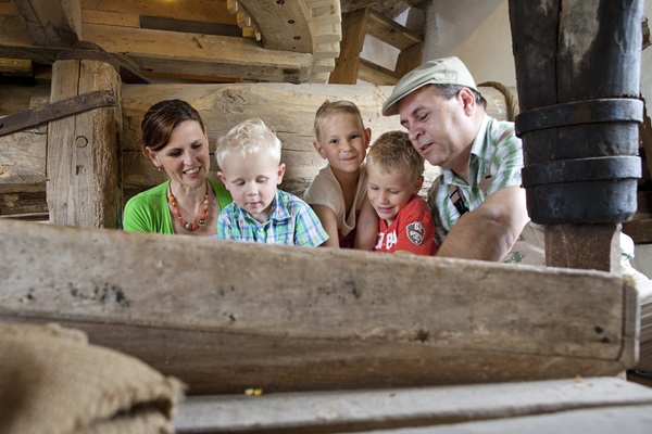 De molenaar laat een vrouw met haar kinderen zien hoe de molen werkt