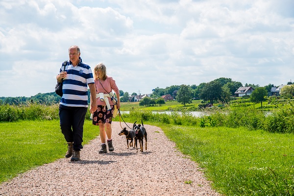 Man en vrouw wandelen met de hondjes langs de Maas