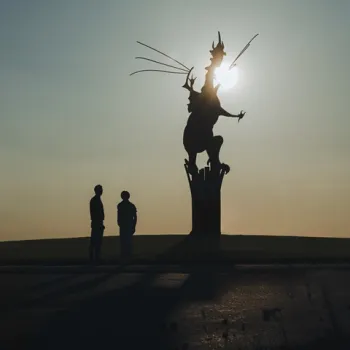 Twee mensen bij de draak op de rotonde in Beesel, gefotografeerd bij zonsondergang als onderdeel van de campagne De Verhalen van Hier
